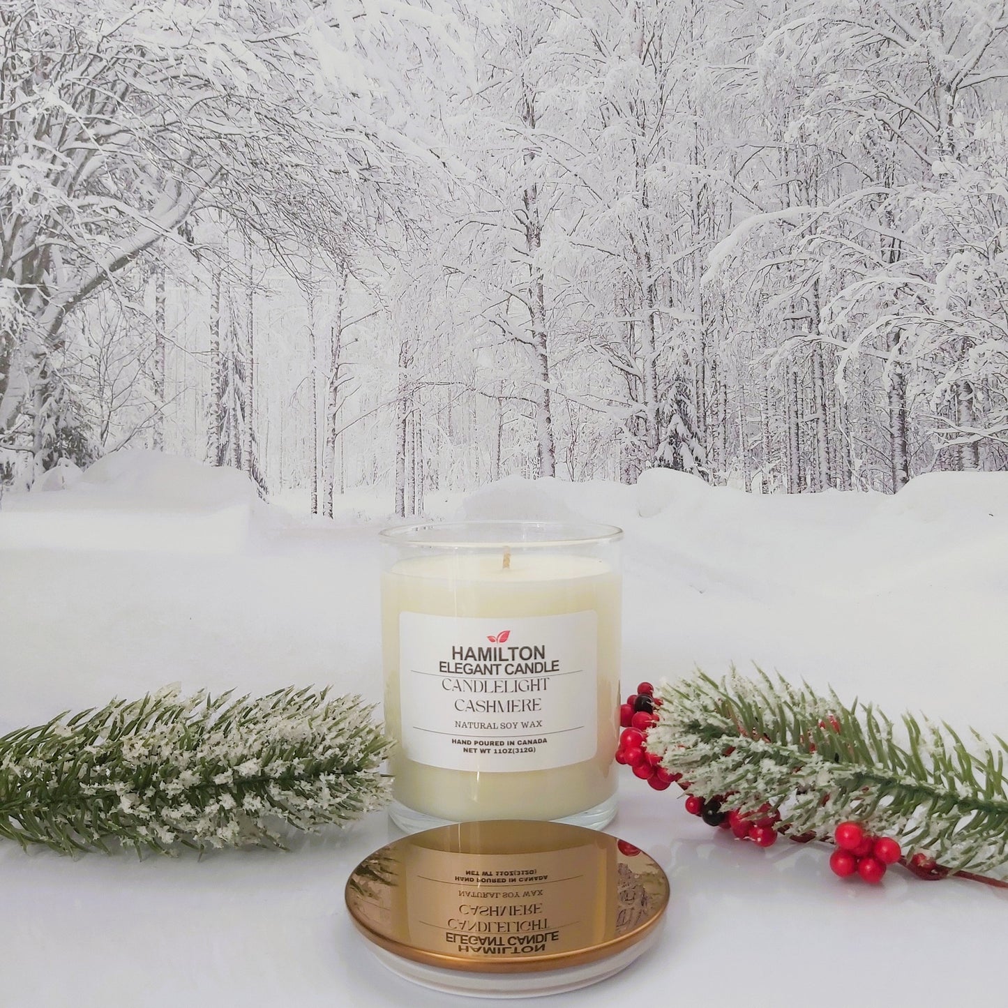 Candle with gold lid on a snowy surface with a winter forest background