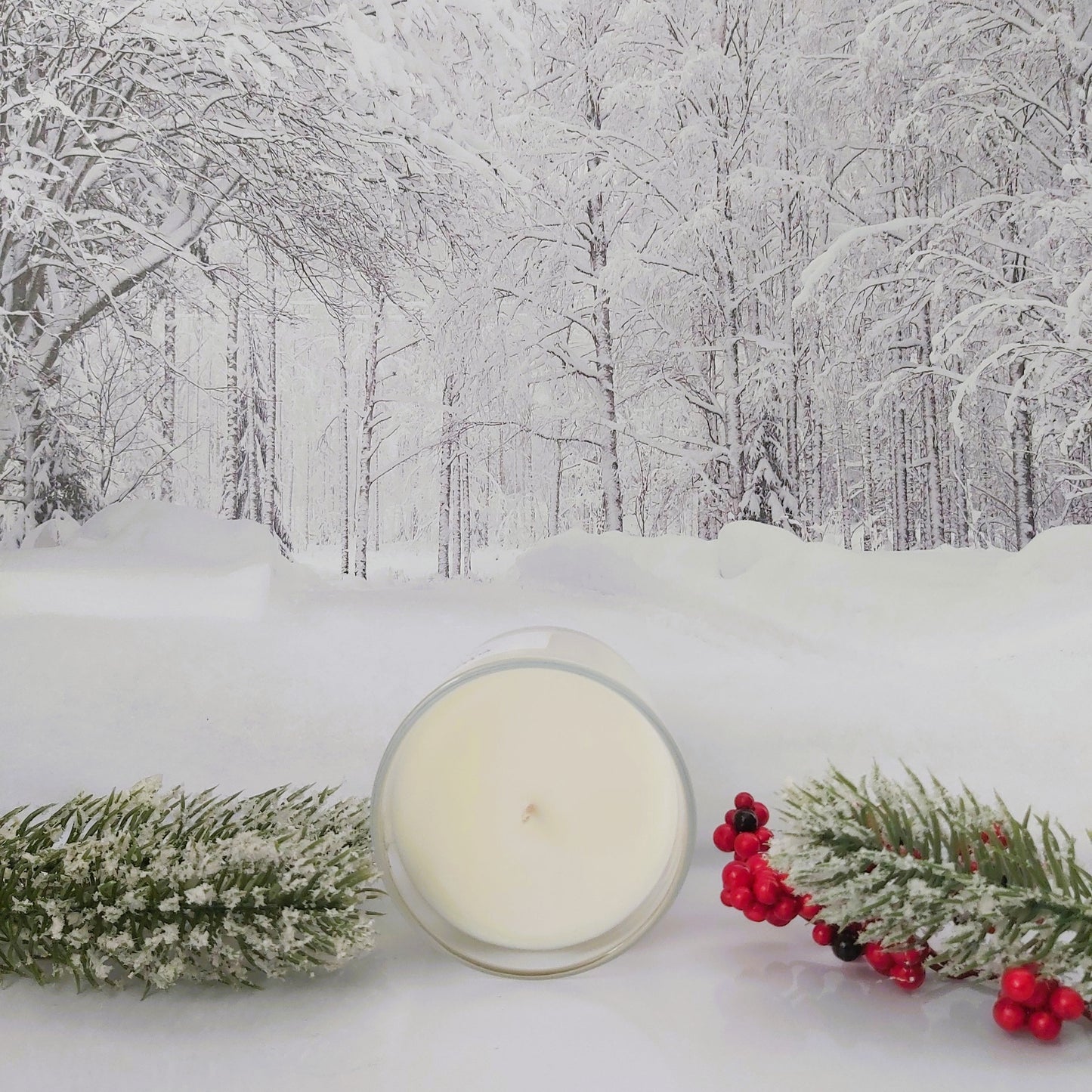 Candle with winter decorations on a snowy background