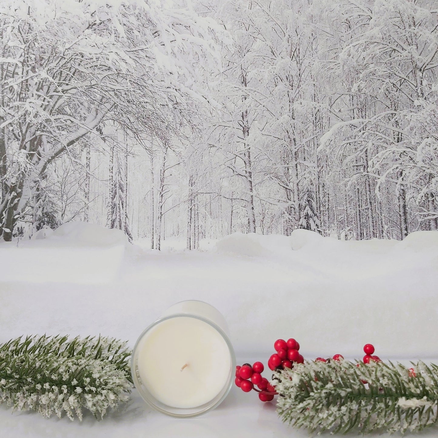 Candle and festive decorations on a snowy forest floor