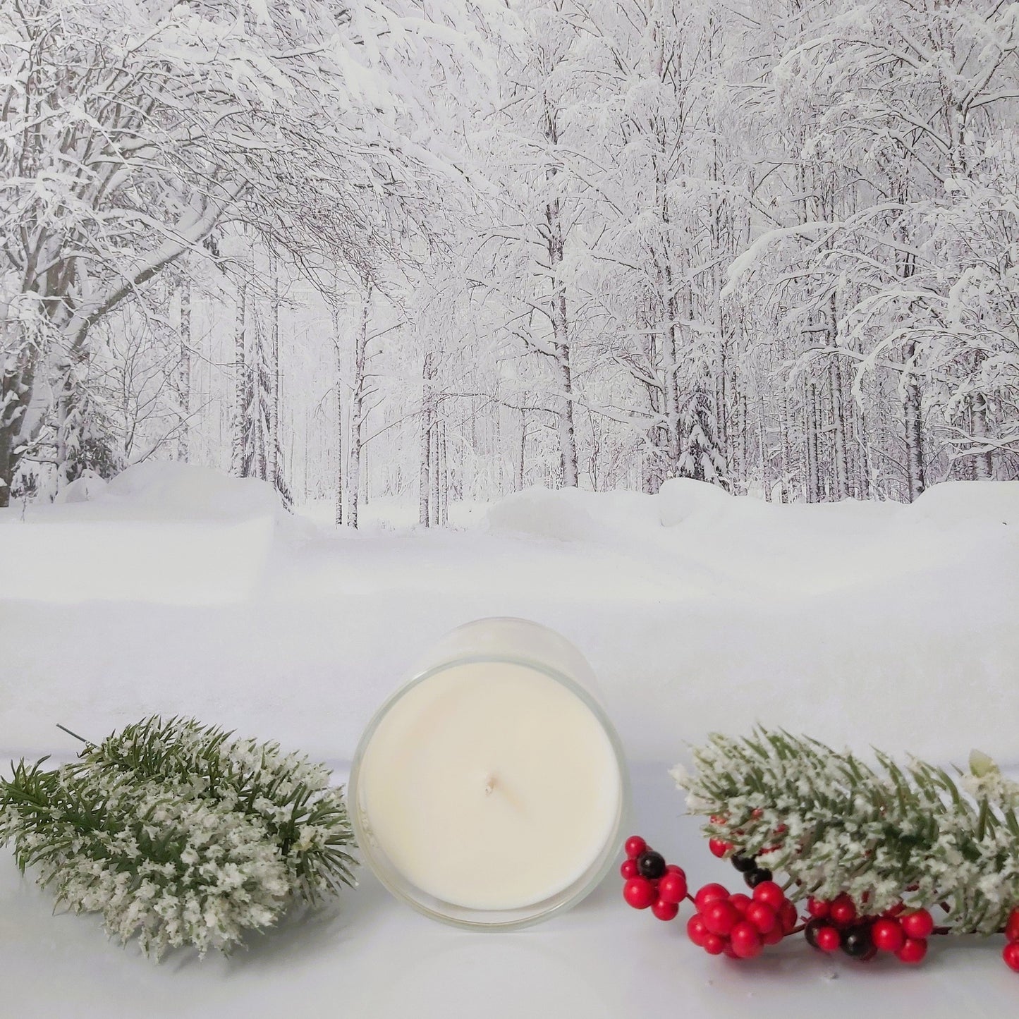 Candle with winter decorations on a snowy background