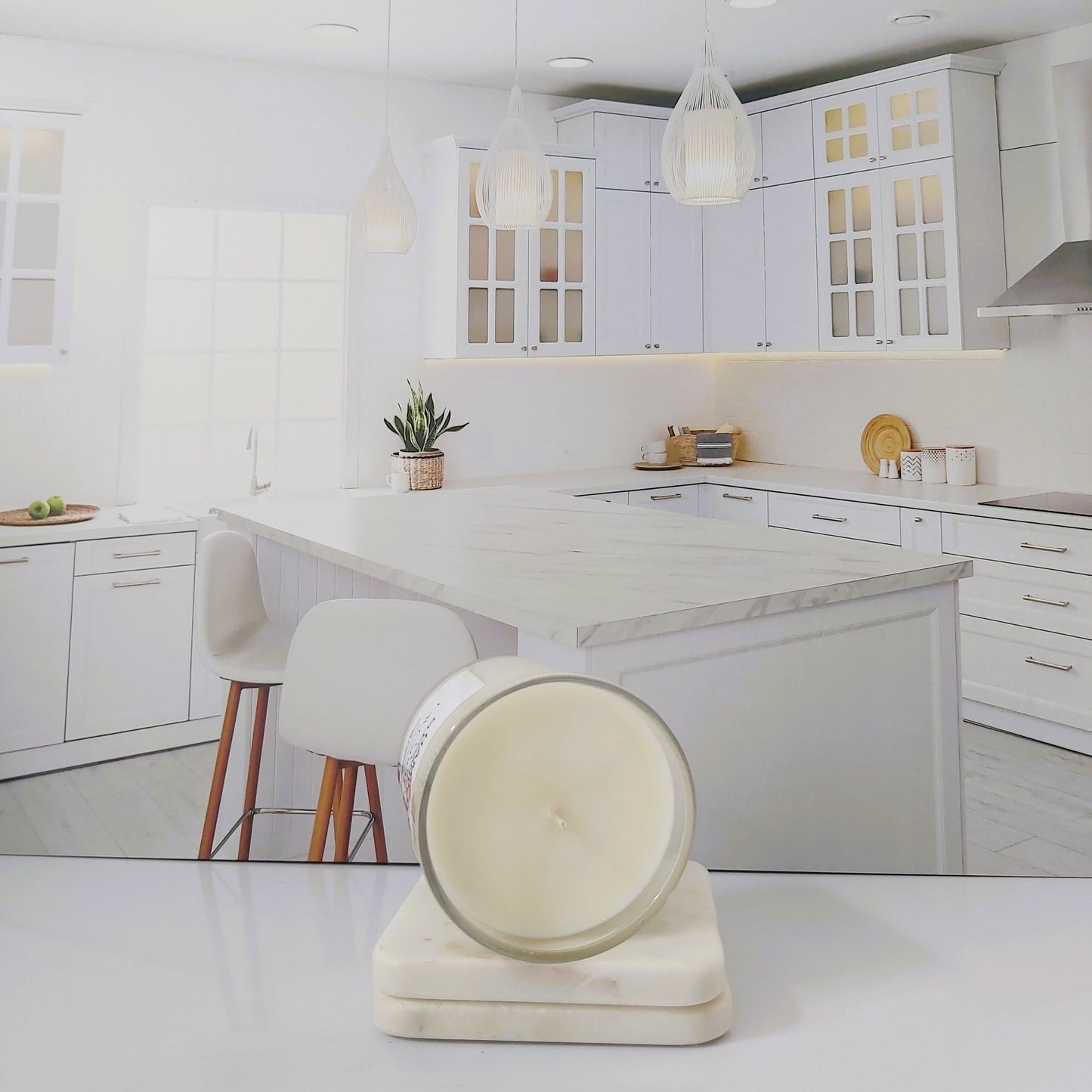 Modern kitchen with white cabinets, marble countertops, and a decorative stool.