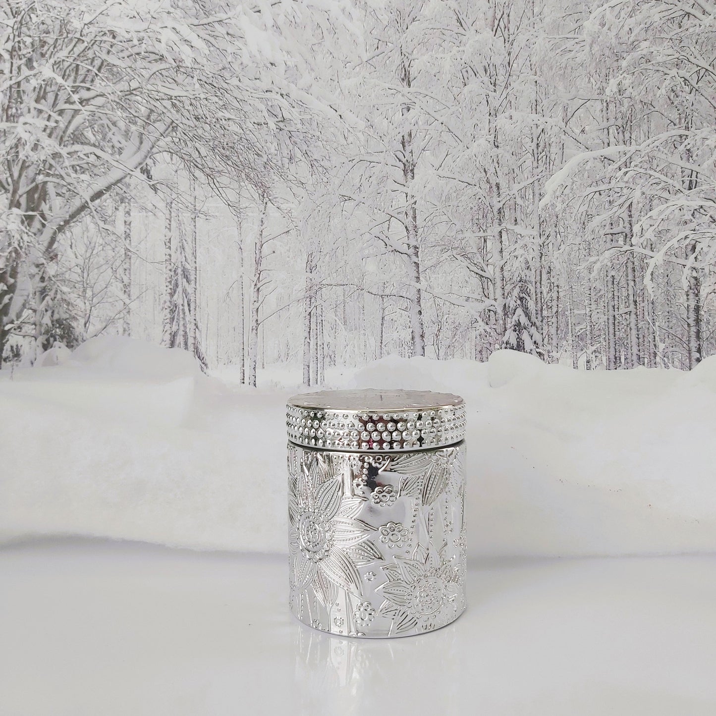 Decorative silver candle holder in a snowy forest