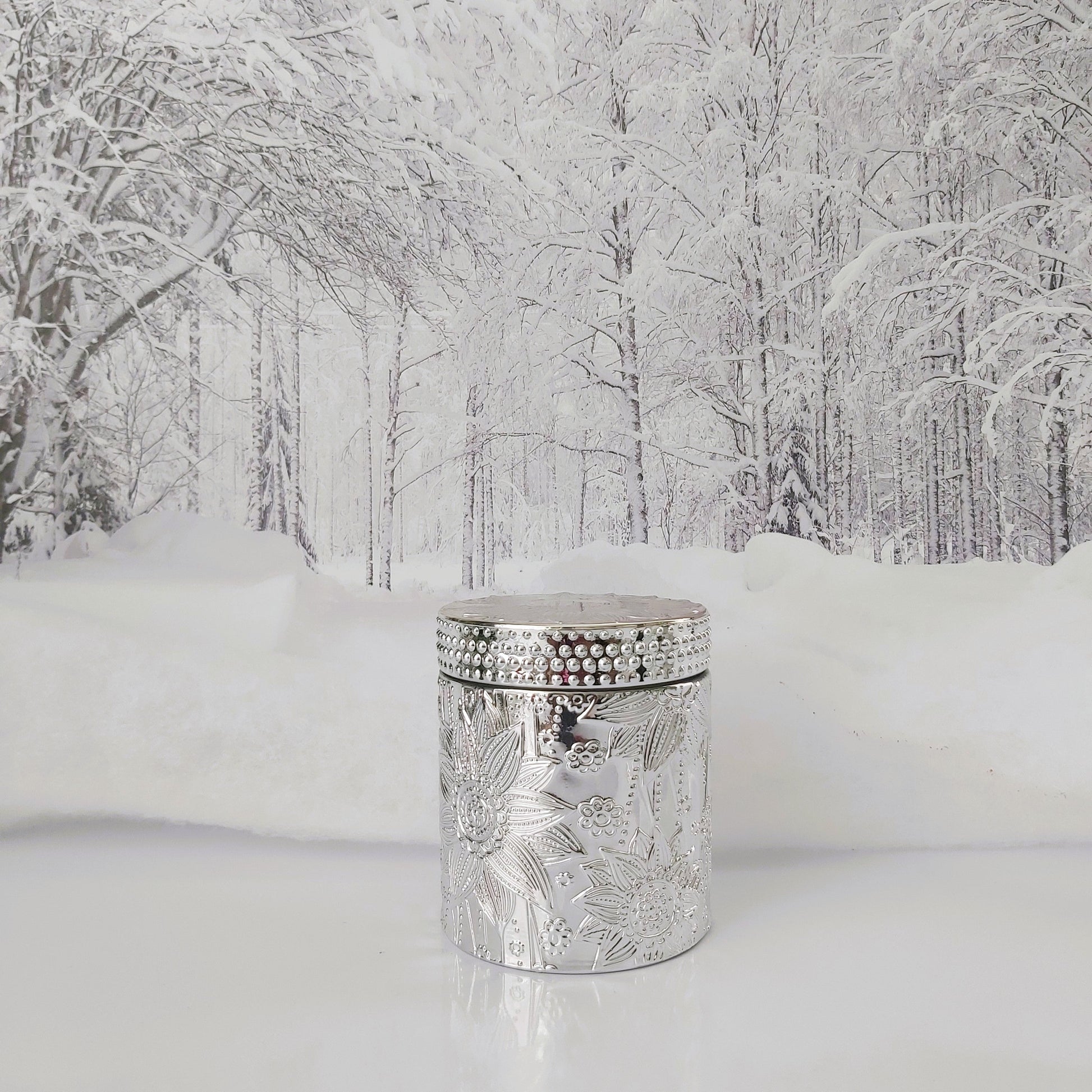 Decorative silver candle holder in a snowy forest