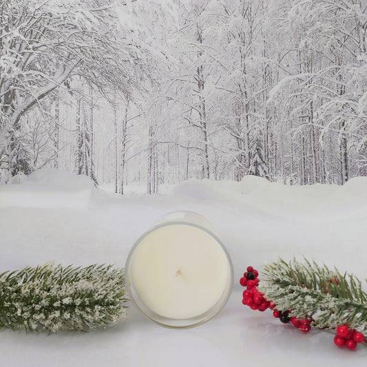 Candle with winter decorations on a snowy background