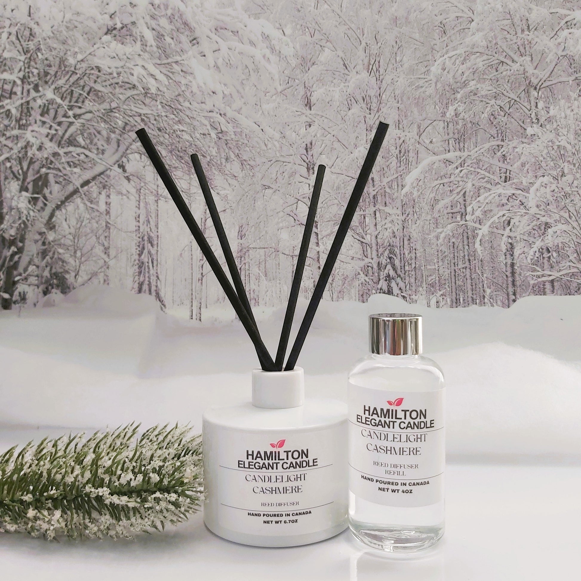 Two diffusers, one with black sticks and one clear bottle, on a snowy landscape background.