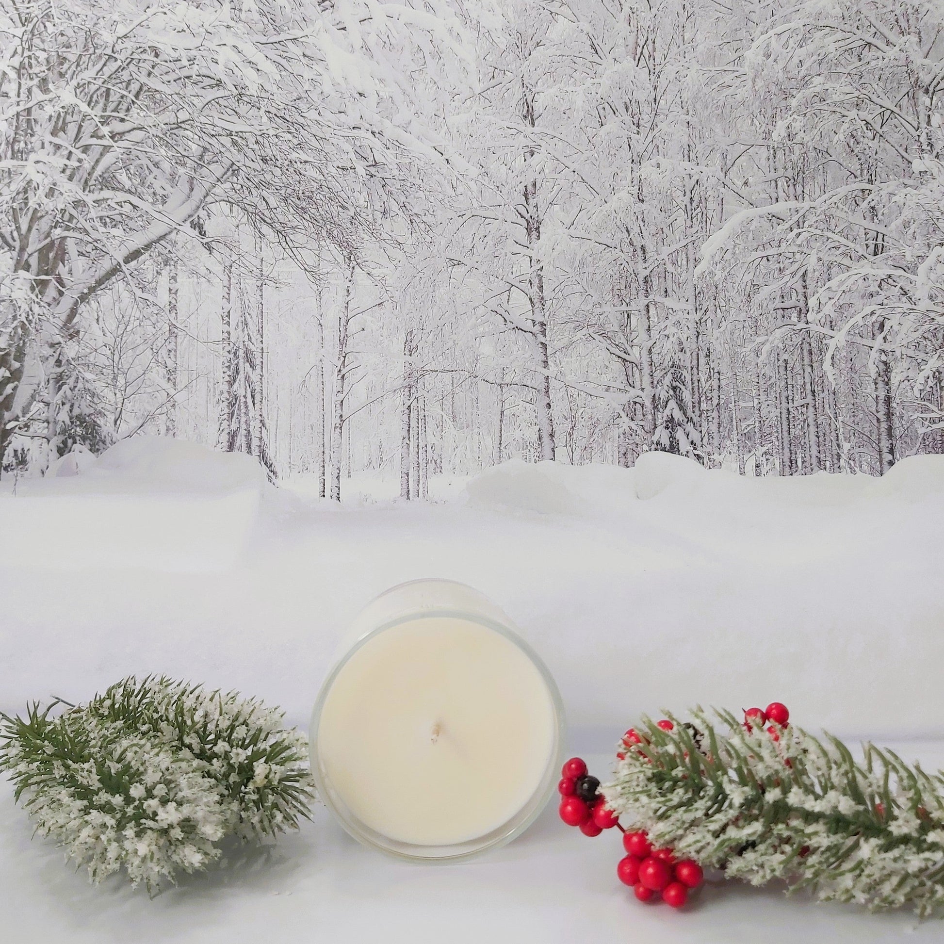 Candle with winter decorations on a snowy background