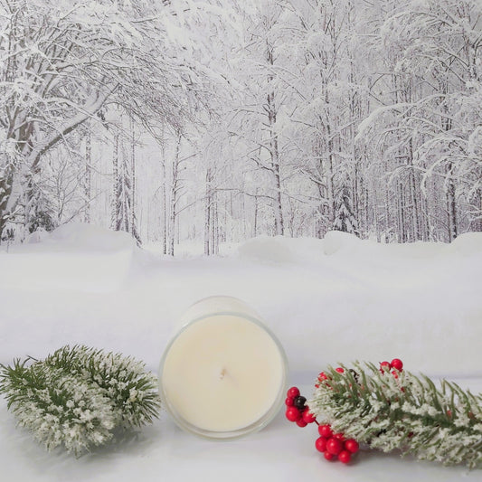 Candle with winter decorations on a snowy background