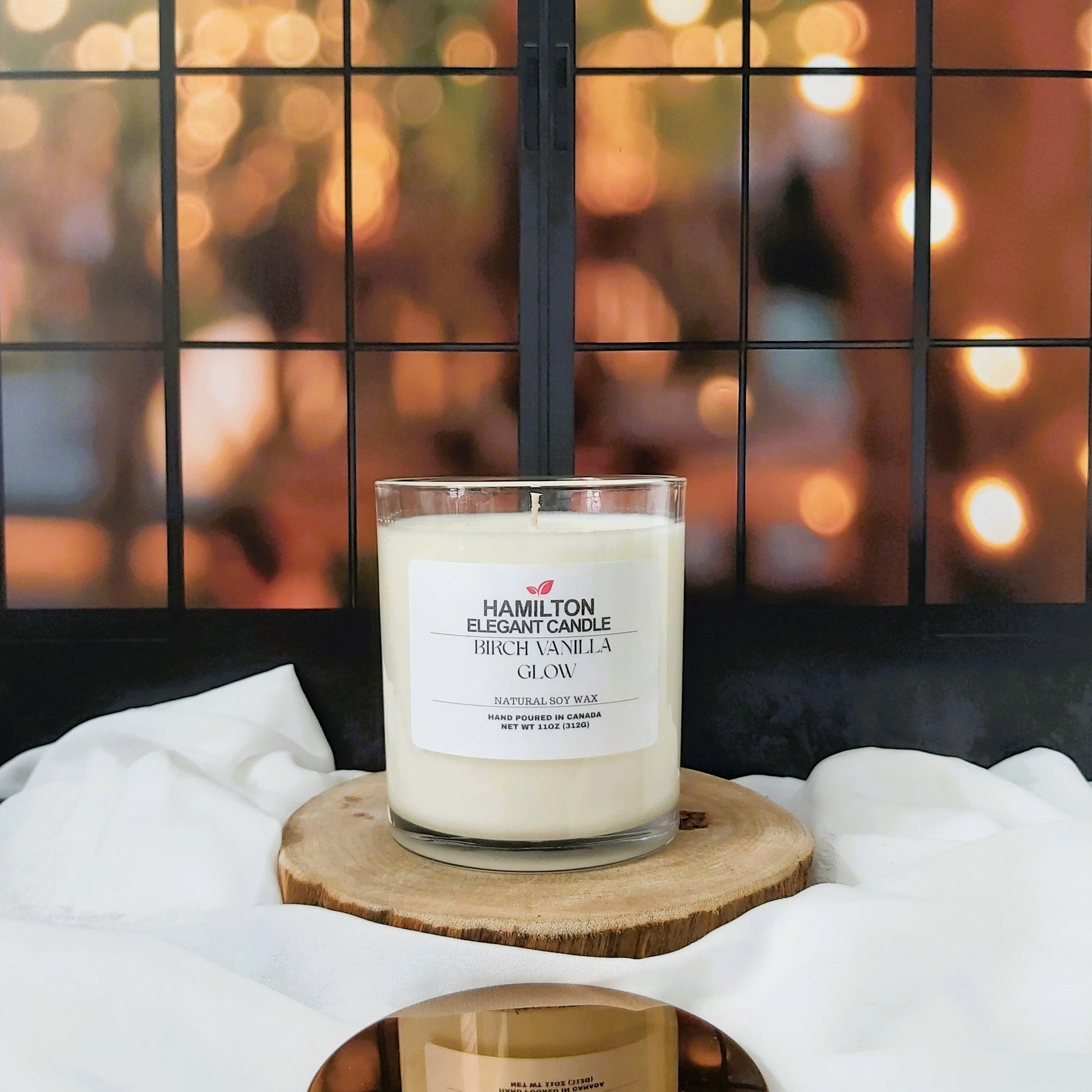 Two candles on a wooden stand with a blurred background of lights