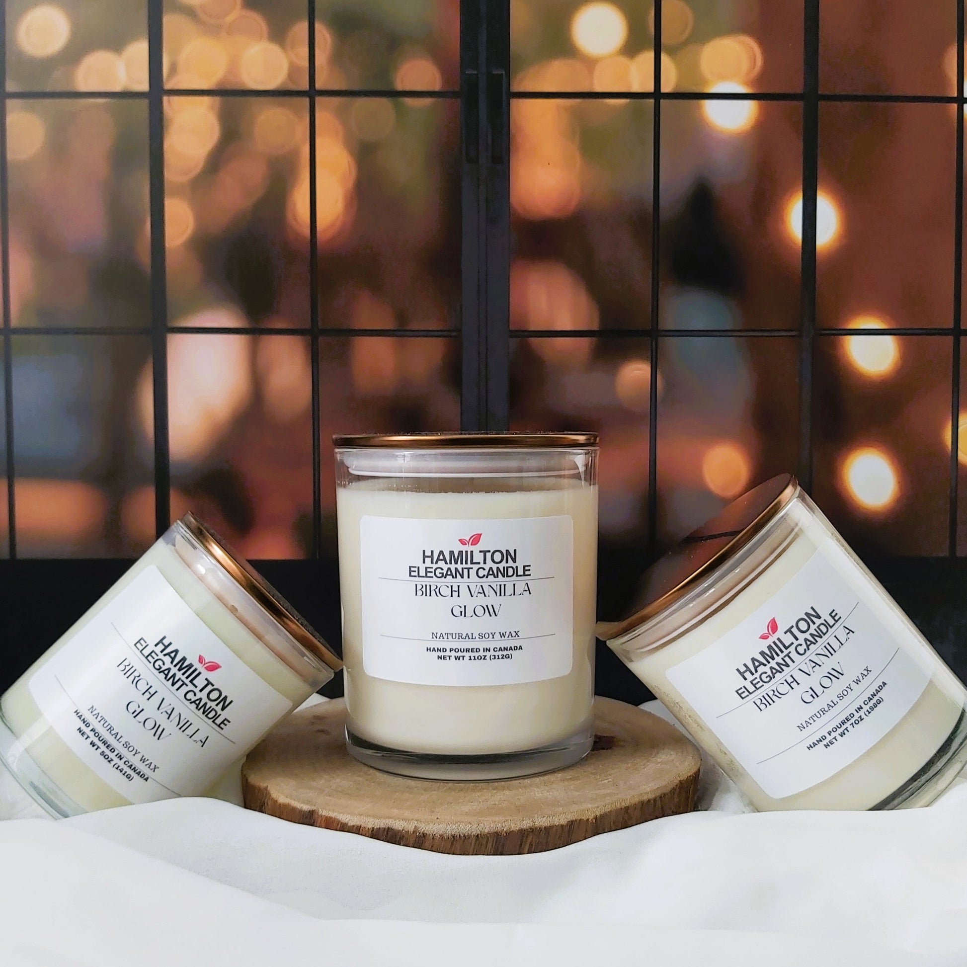 Three candles on a wooden coaster with a blurred background of lights