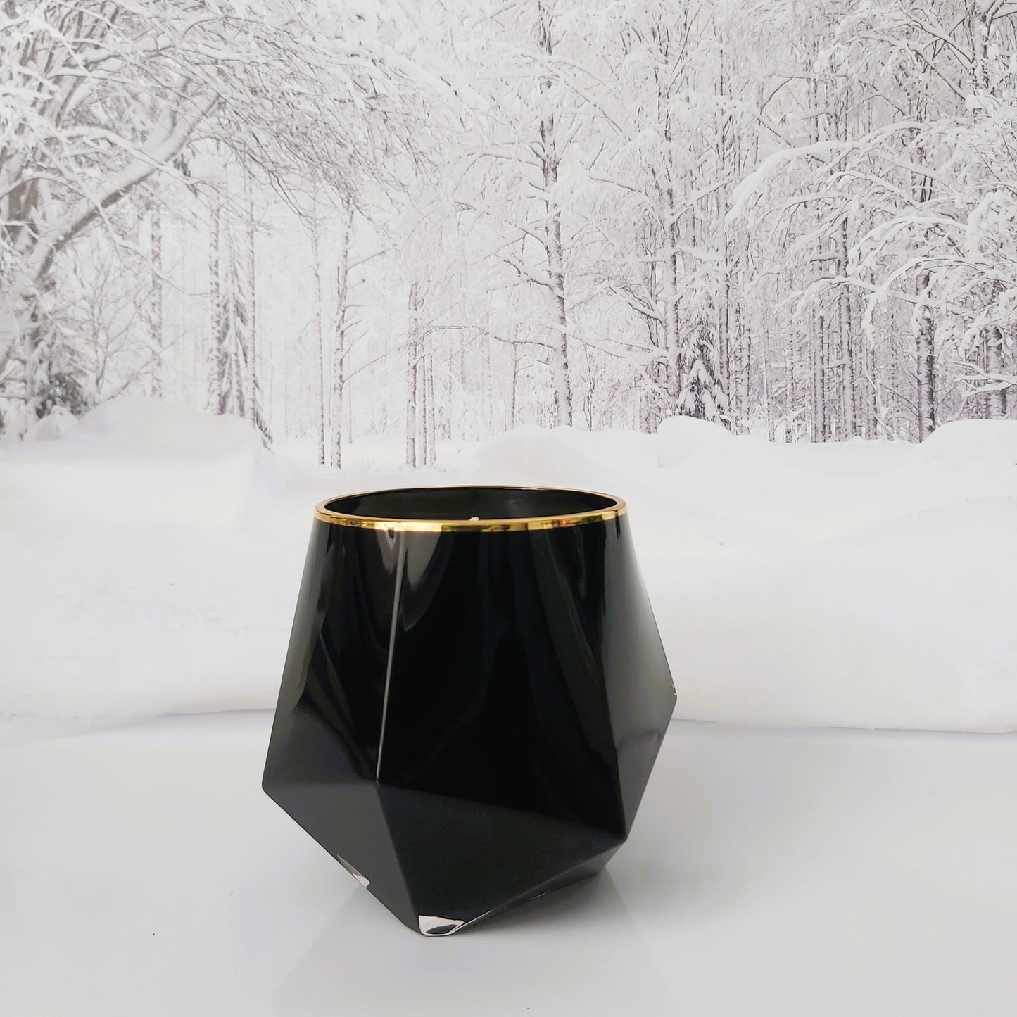 Black geometric vase with gold rim on a snowy landscape