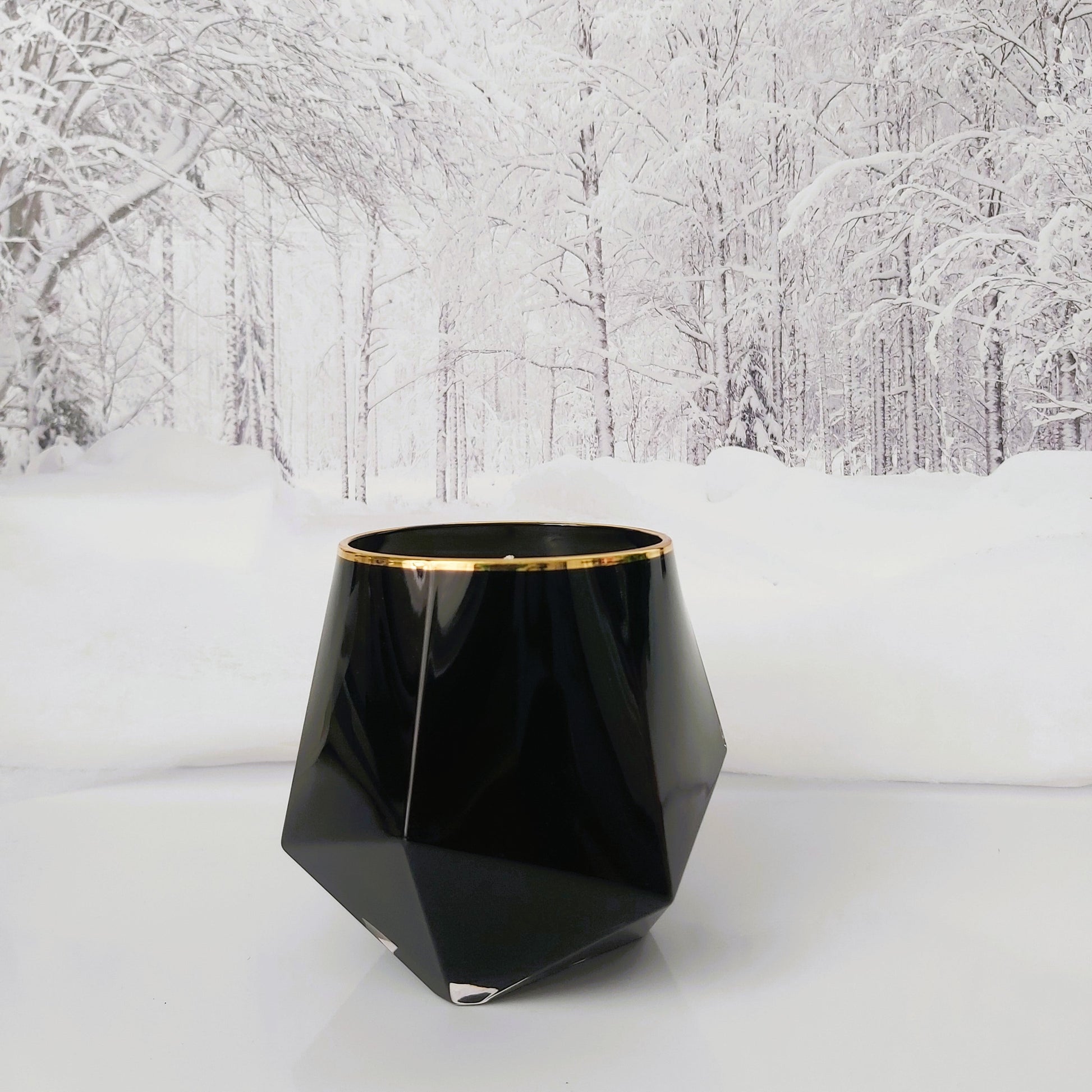 Black geometric vase with gold rim on a snowy landscape