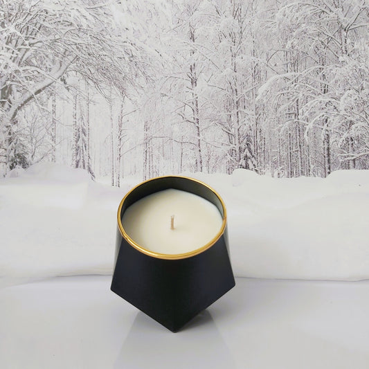 Black candle jar on a snowy surface with trees in the background