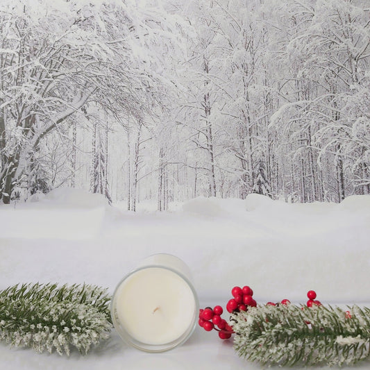 Candle and festive decorations on a snowy forest floor