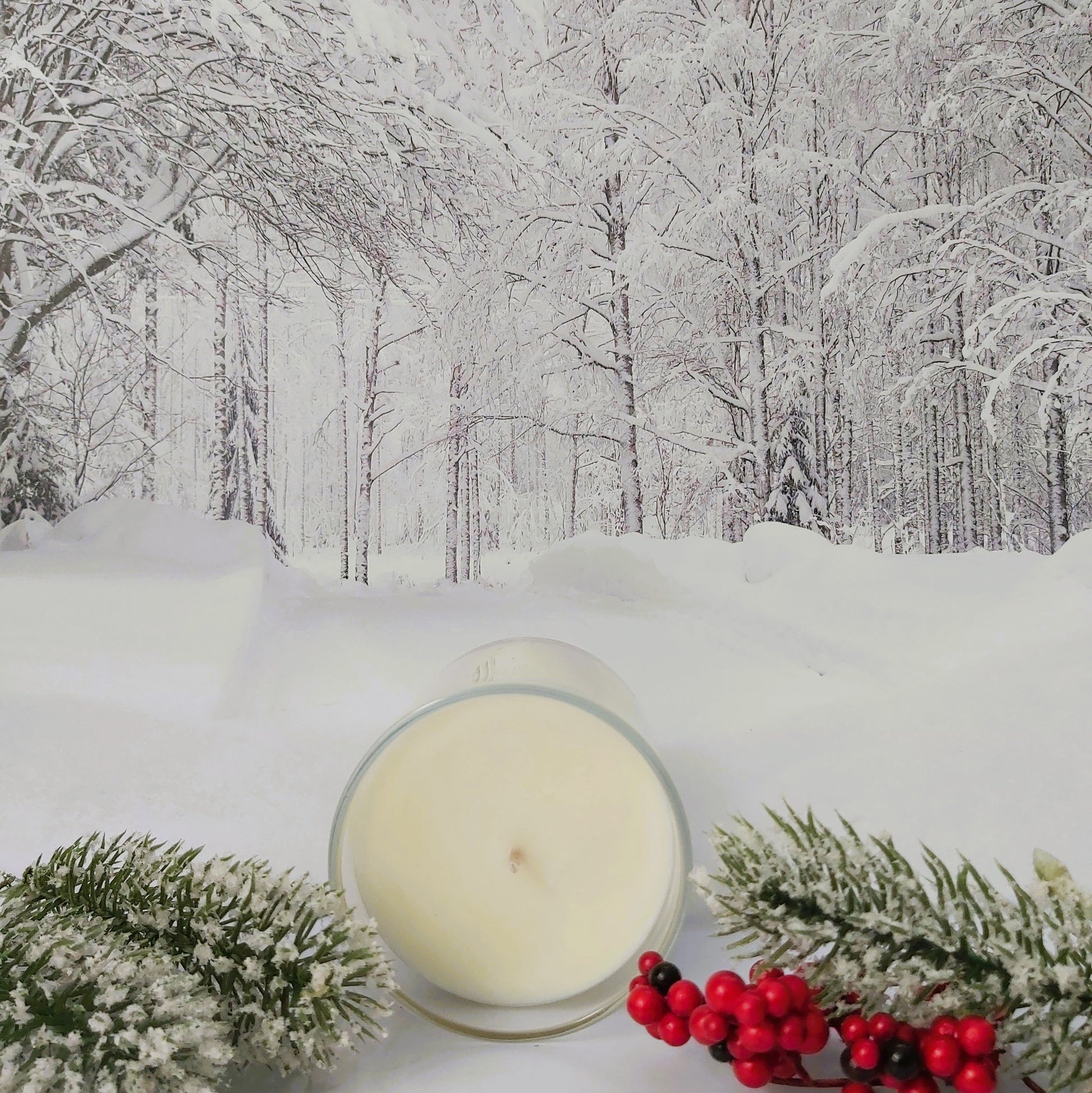 Candle with winter decorations on a snowy forest background