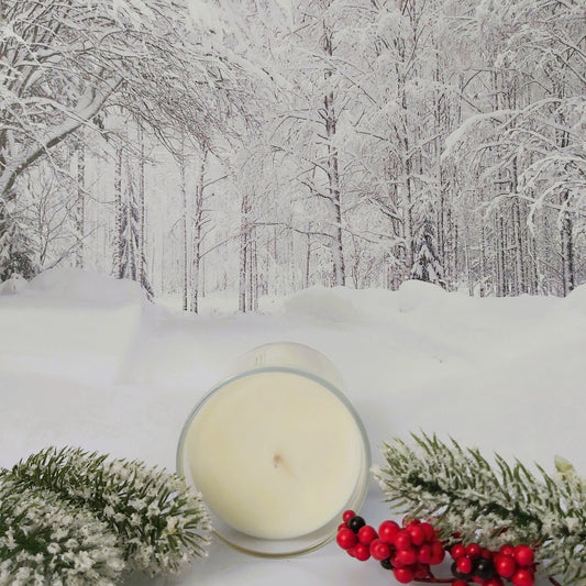 Candle with winter decorations on a snowy forest background