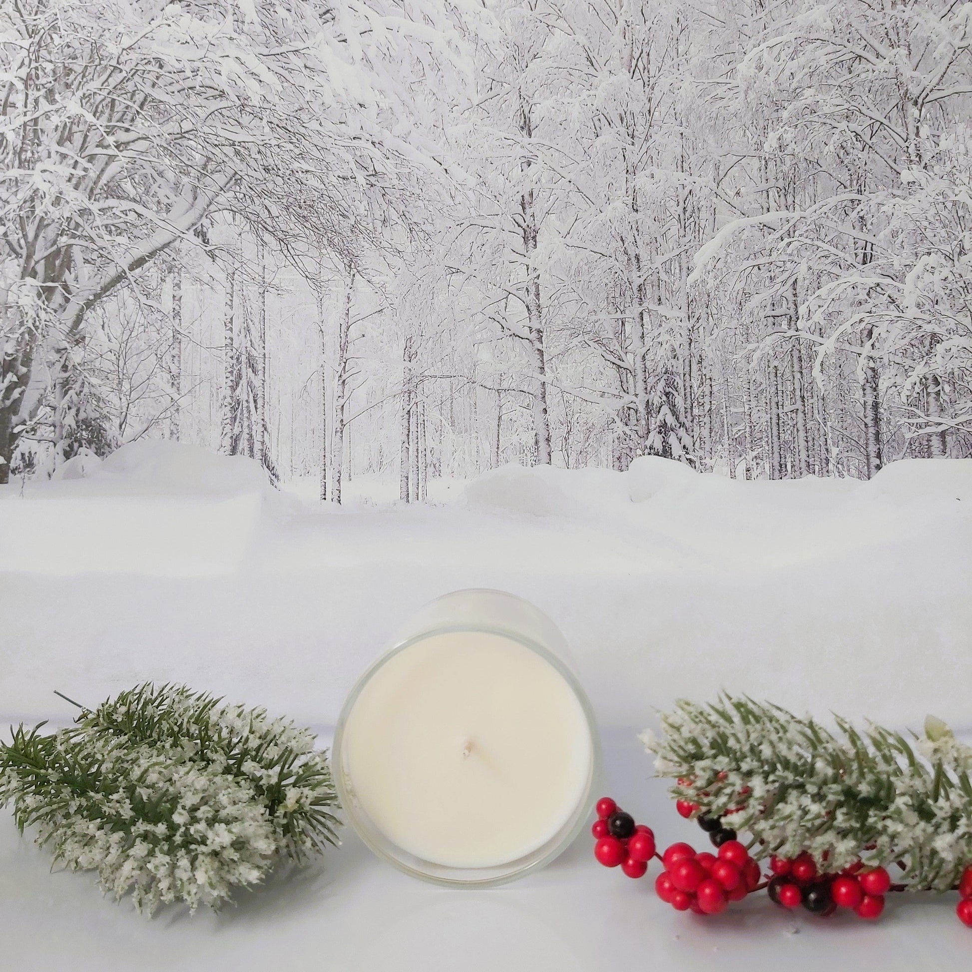 Candle with winter decorations on a snowy background