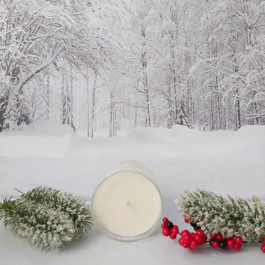 Candle with winter decorations on a snowy background