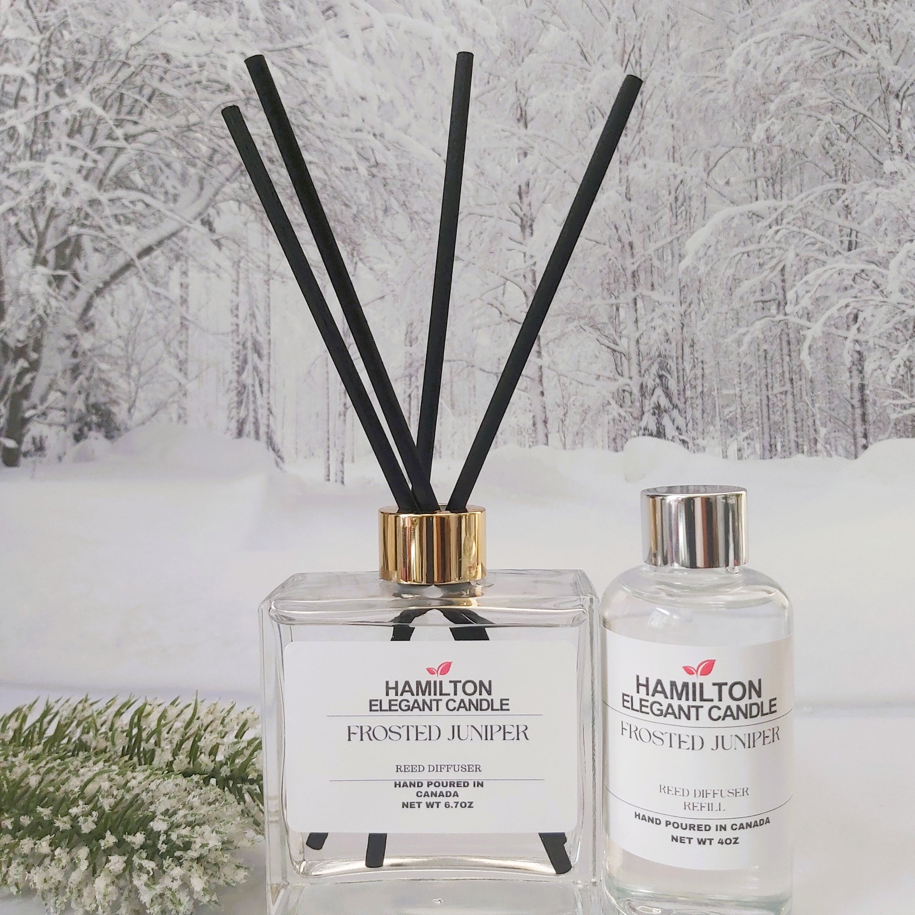 Two diffusers with black reeds against a snowy forest background