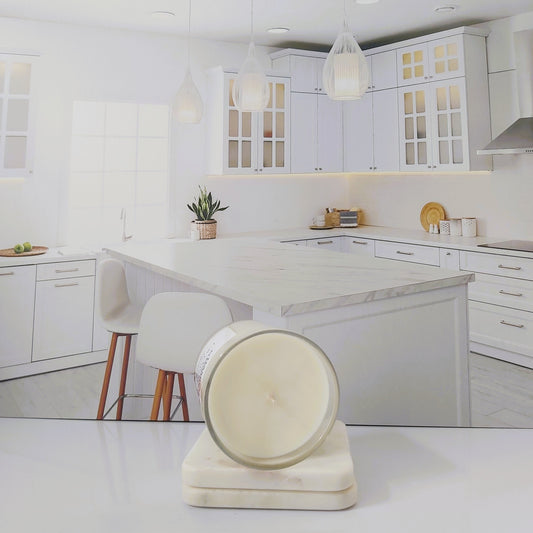 Modern kitchen with white cabinets, marble countertops, and a decorative stool.