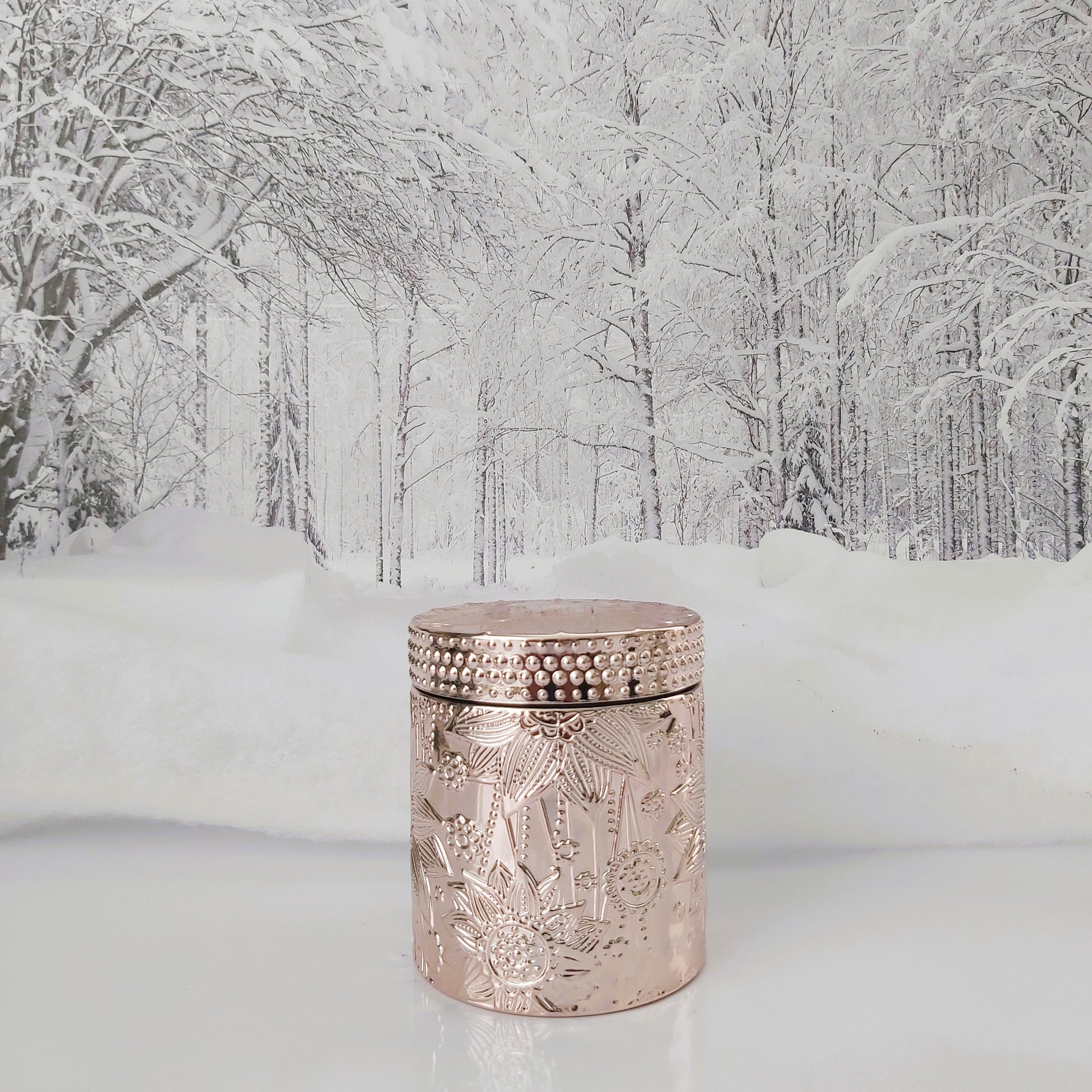 Decorative cylindrical jar with intricate design in a snowy forest setting